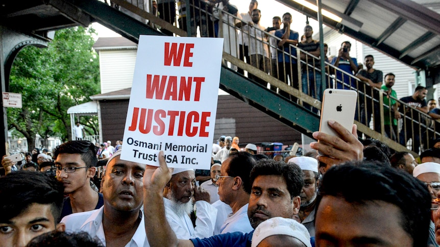 A crowd of Muslim community members gather in New York holding a sign that reads "we want justice".