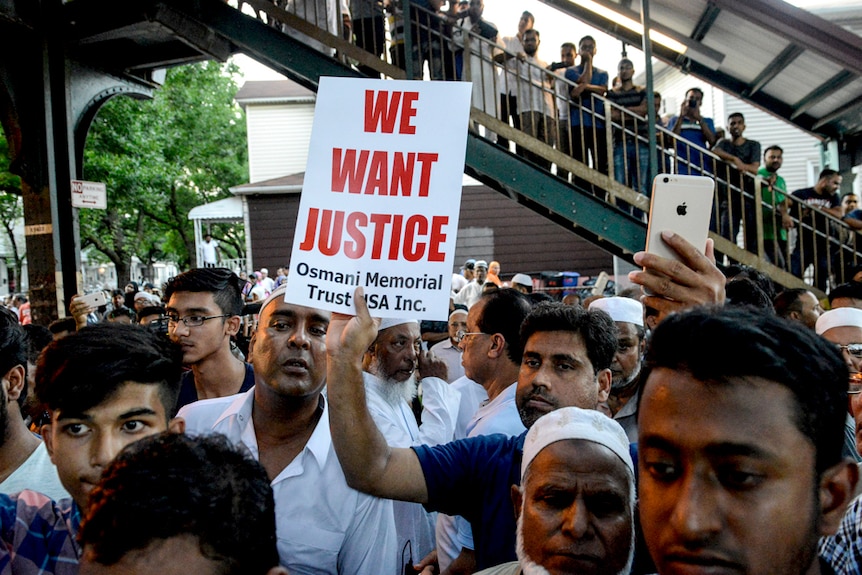 A crowd of Muslim community members gather in New York holding a sign that reads "we want justice".