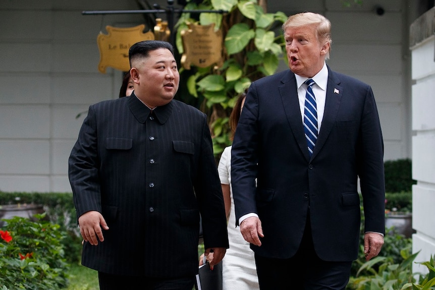 Kim Jong-un and Donald  Trump walking along a path.