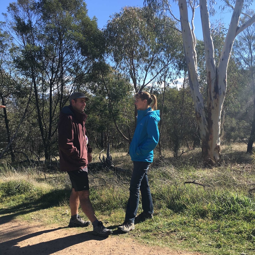 Matt Napier and his wife Wendy standing, looking at each other on a bush trail.