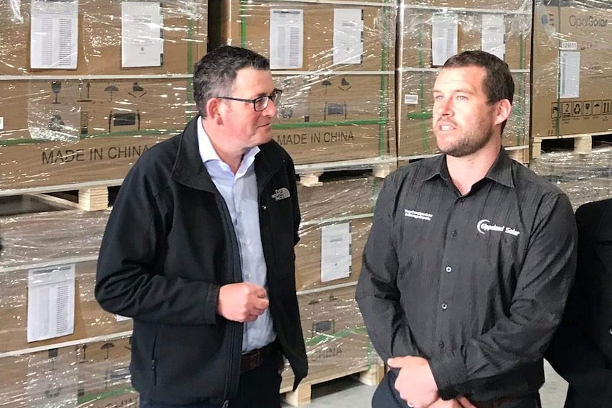 Daniel Andrews tours a warehouse storing solar panels.