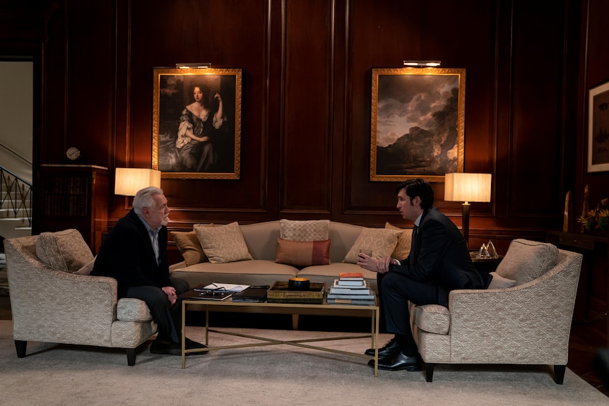 Still from TV show Succession of an old man in a suit sitting opposite a man in his early 30s in a suit in a formal living room