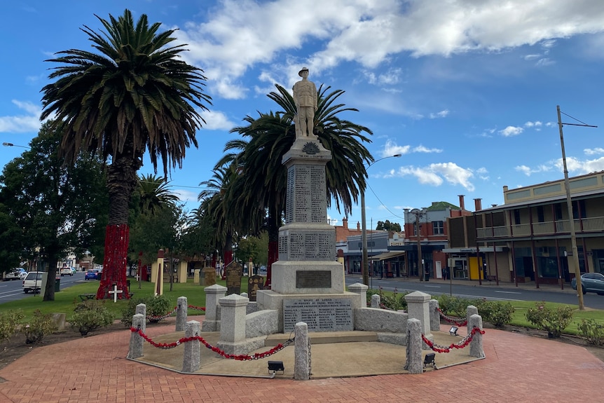 A war memorial in the centre of a town with palm trees behind