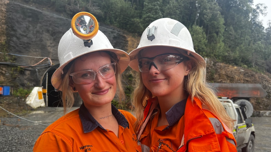 Two women in helmet and with safety glasses stand outside a mine portal in Tasmania to discuss the increased demand for nickel. 