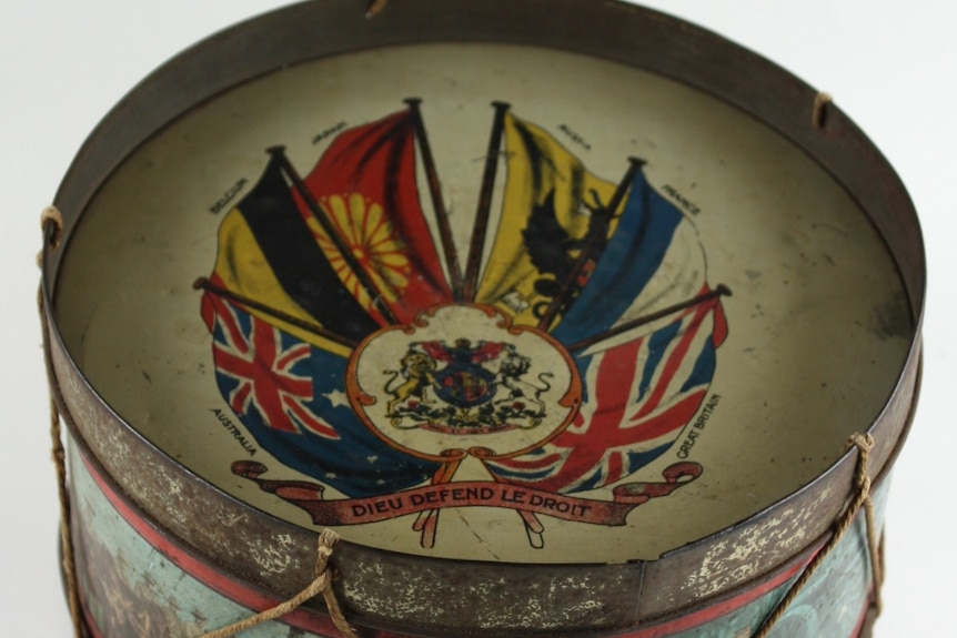 World War One toy tine drum with pictures of allied flags and soldiers.