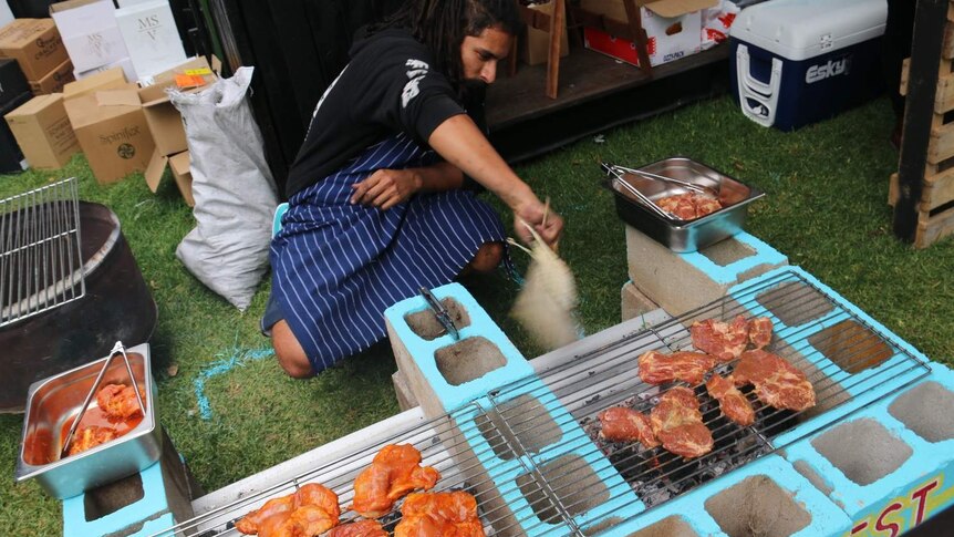 A man cooks meat on a barbecue.