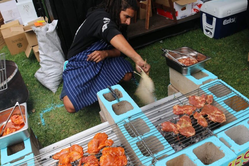 A man cooks meat on a barbecue.