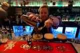 Woman bartender pourning expresso martinis into four classes