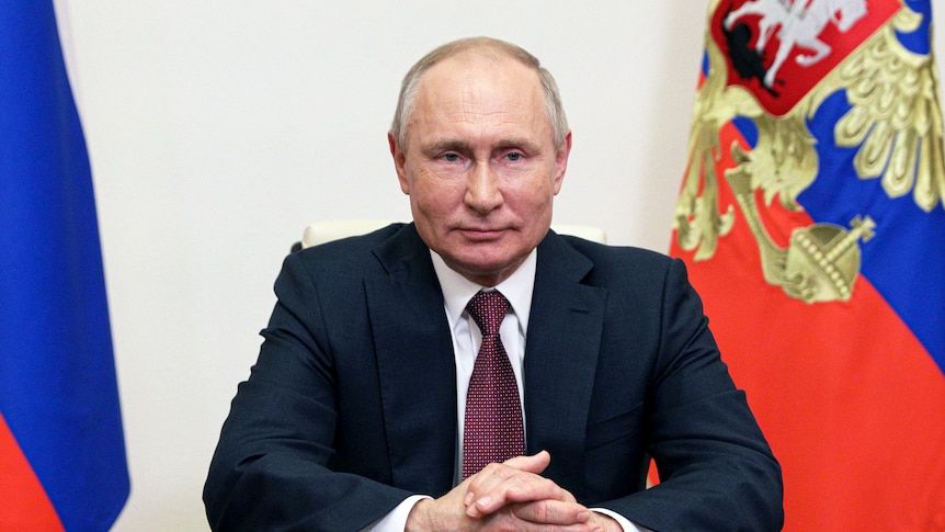 Russian President Vladimir Putin is sitting at a desk