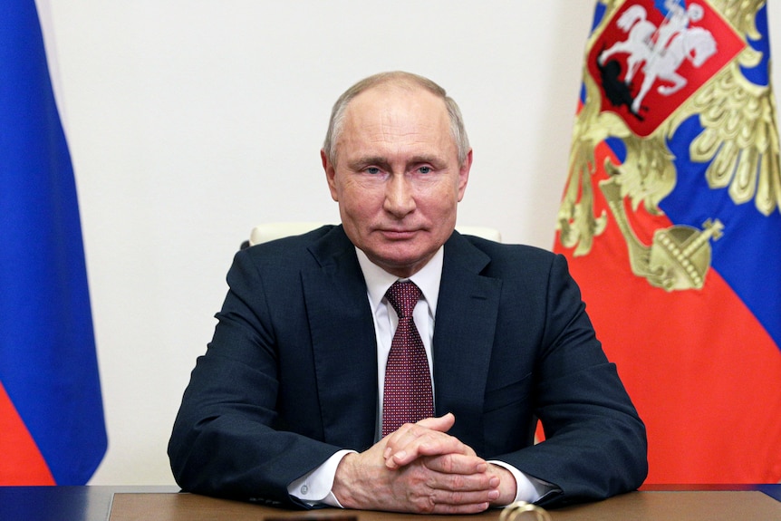 Russian President Vladimir Putin sits at a desk