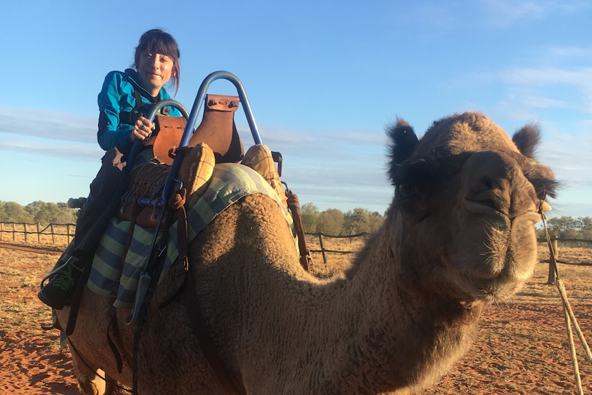 A woman riding a camel in the outback