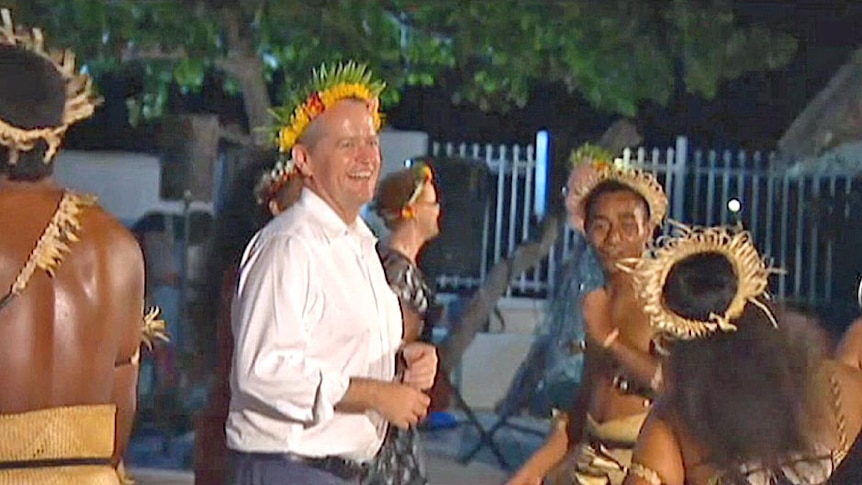 Bill Shorten, wearing a floral head-dress, dances while visiting the island republic of Kiribati.
