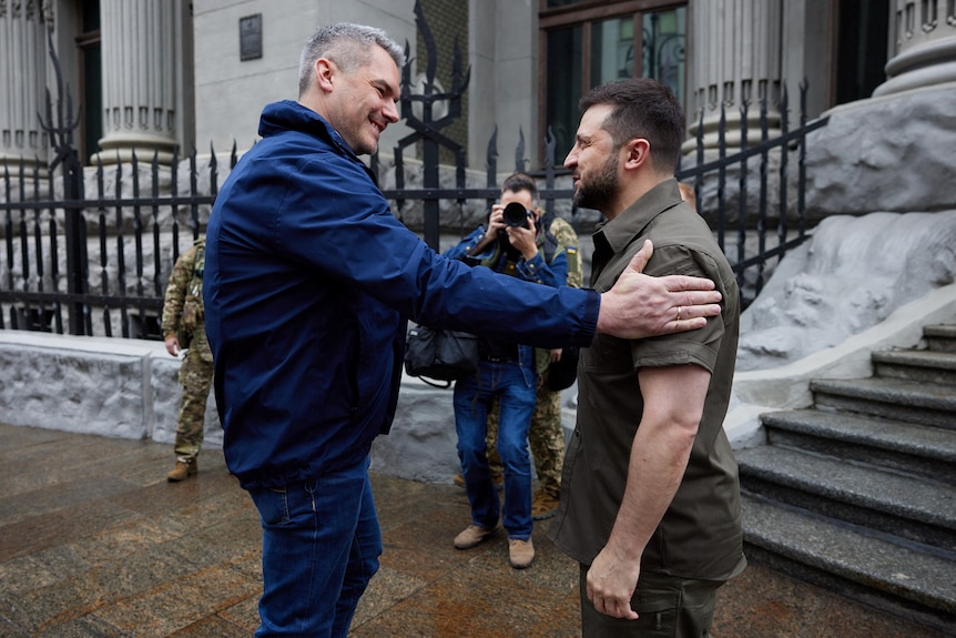 Ukrainian President Volodymyr Zelenskyy welcomes Austrian Chancellor Karl Nehammer outside building.