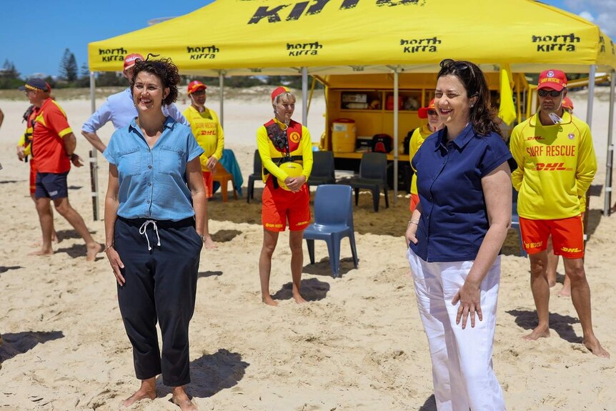 Premier Annastacia Palaszczuk on a beach surrounded by lifeguards.