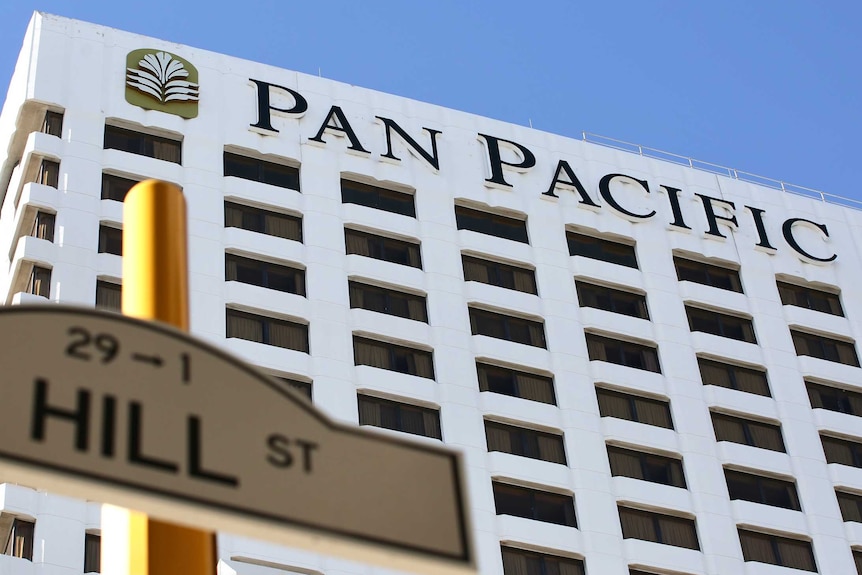 A low angle of the Pan Pacific hotel in Perth with a blue sky background, in the fore is a St sign
