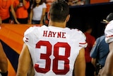 View from behind of Jarryd Hayne in his San Francisco 49ers number 38 jersey walking off the field with crowd in the distance.