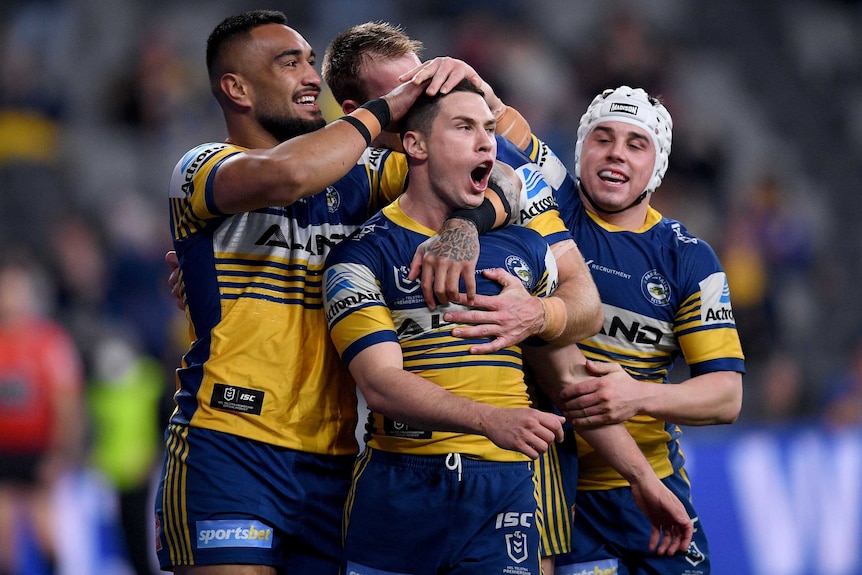 Parramatta Eels NRL players embrace as they celebrate a try against Wests Tigers.