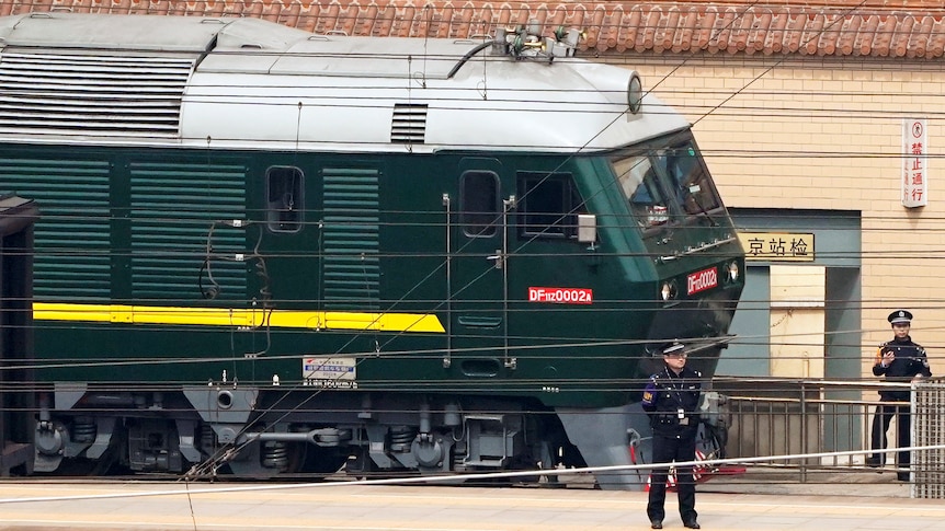 Police officers stand on a platform and keep watch next to a green train at Beijing Railway Station in Beijing.