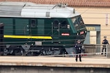 Police officers stand on a platform and keep watch next to a green train at Beijing Railway Station in Beijing.