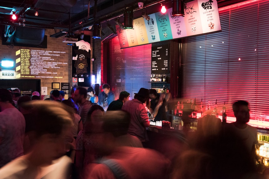 night club with patrons at a bar and neon signs