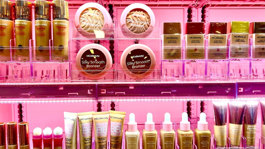 A number of beauty products placed on a vibrant pink display stand.