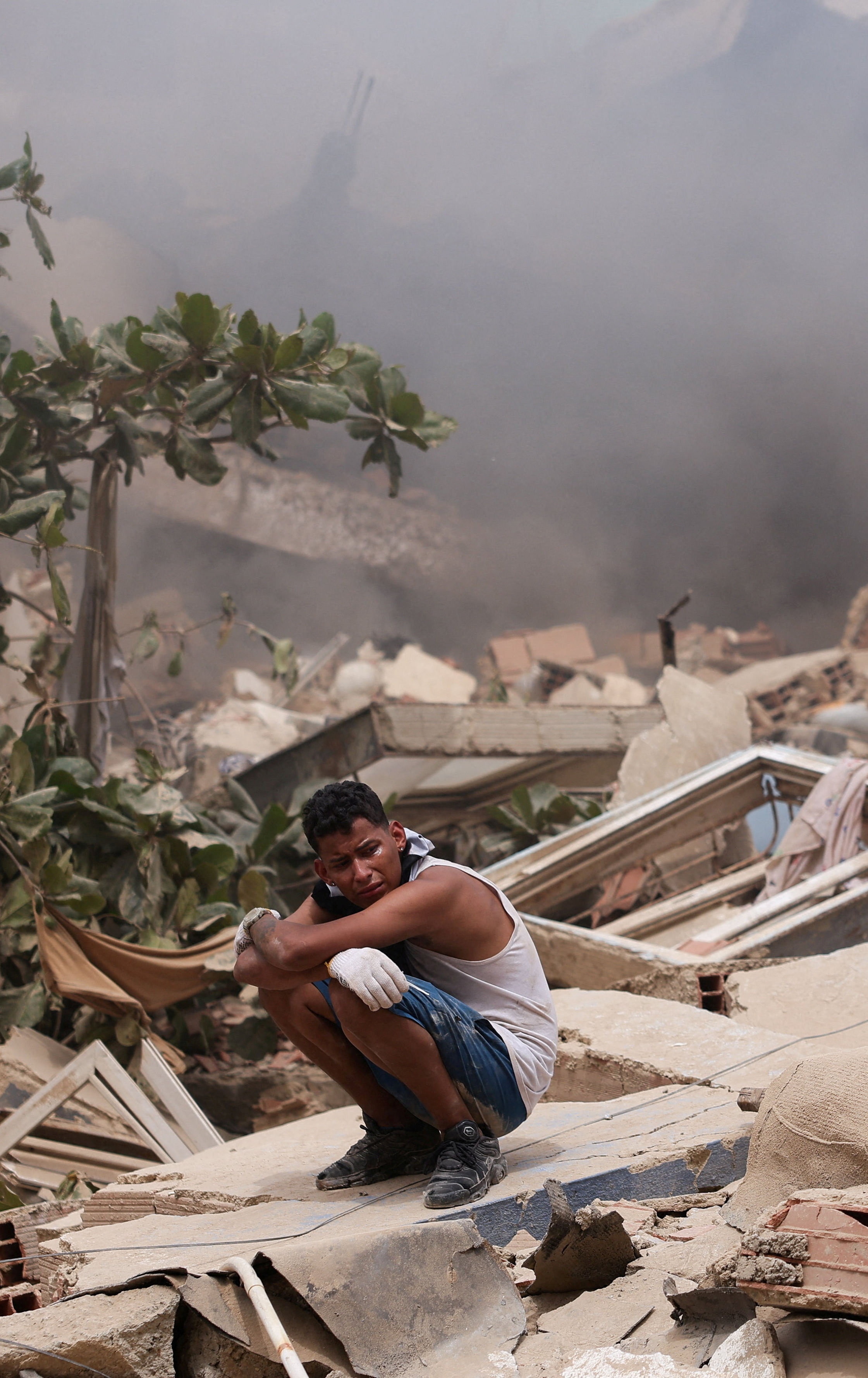a man crouches on rubble 