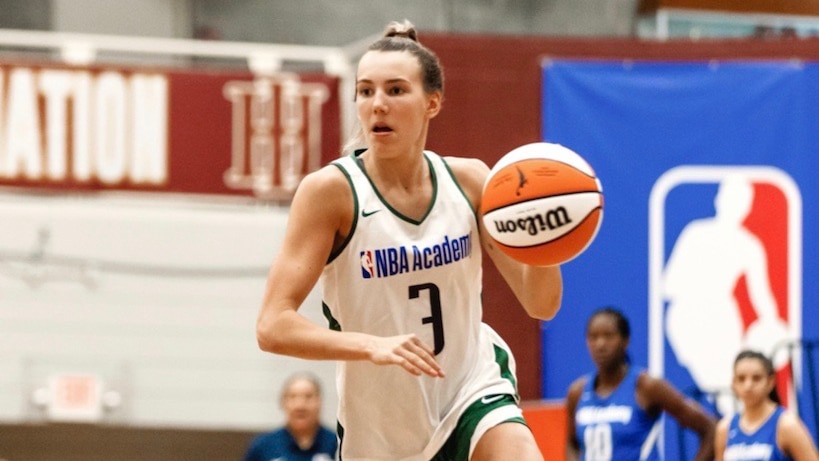 A girl about to bounce a basketball on a court while running
