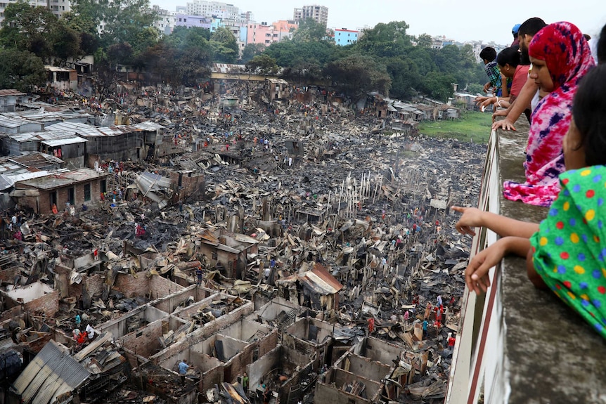 People on a balcony look down onto a burnt-out slum.