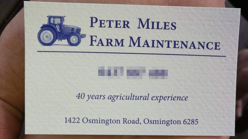 A hand holds Peter Miles' farm maintenance business card.