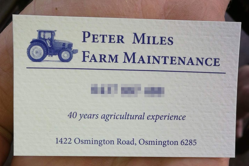 A hand holds Peter Miles' farm maintenance business card.