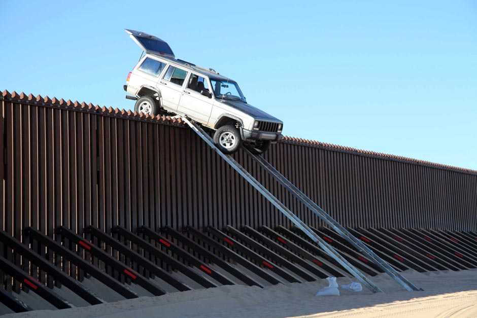 A vehicle sits stuck atop the US-Mexico border fence.