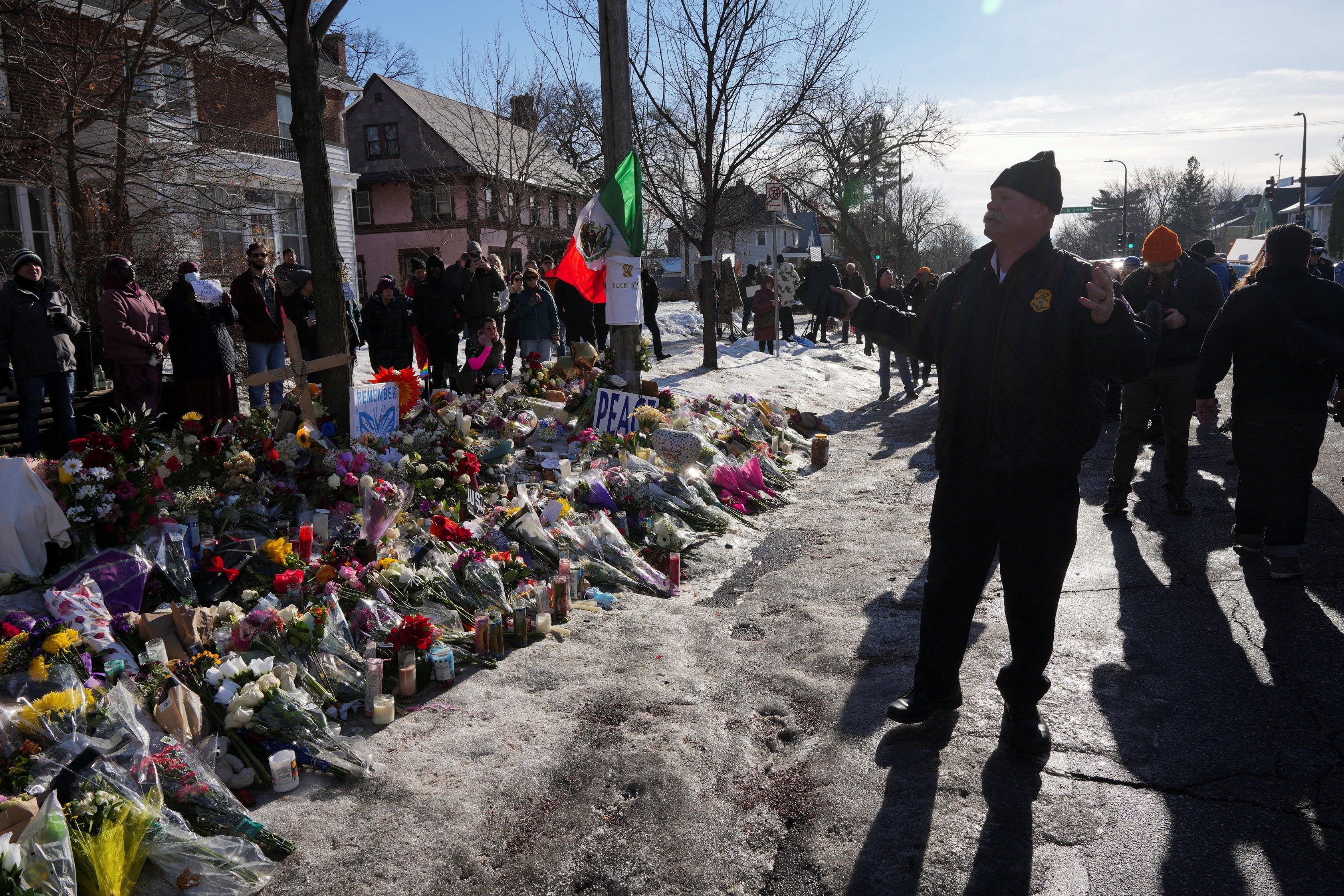 Las flores se alinean en una calle mientras un oficial de policía habla con la gente. 