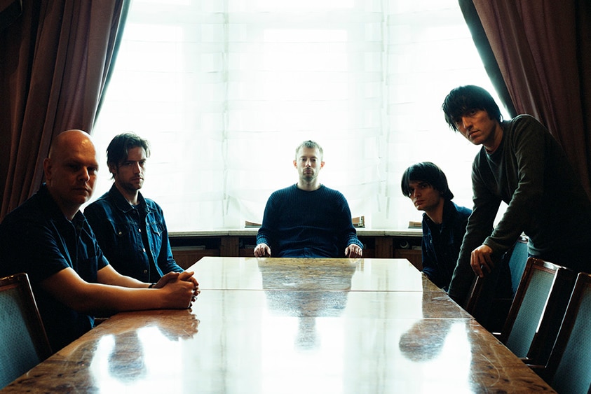 Band members sit around a boardroom table.