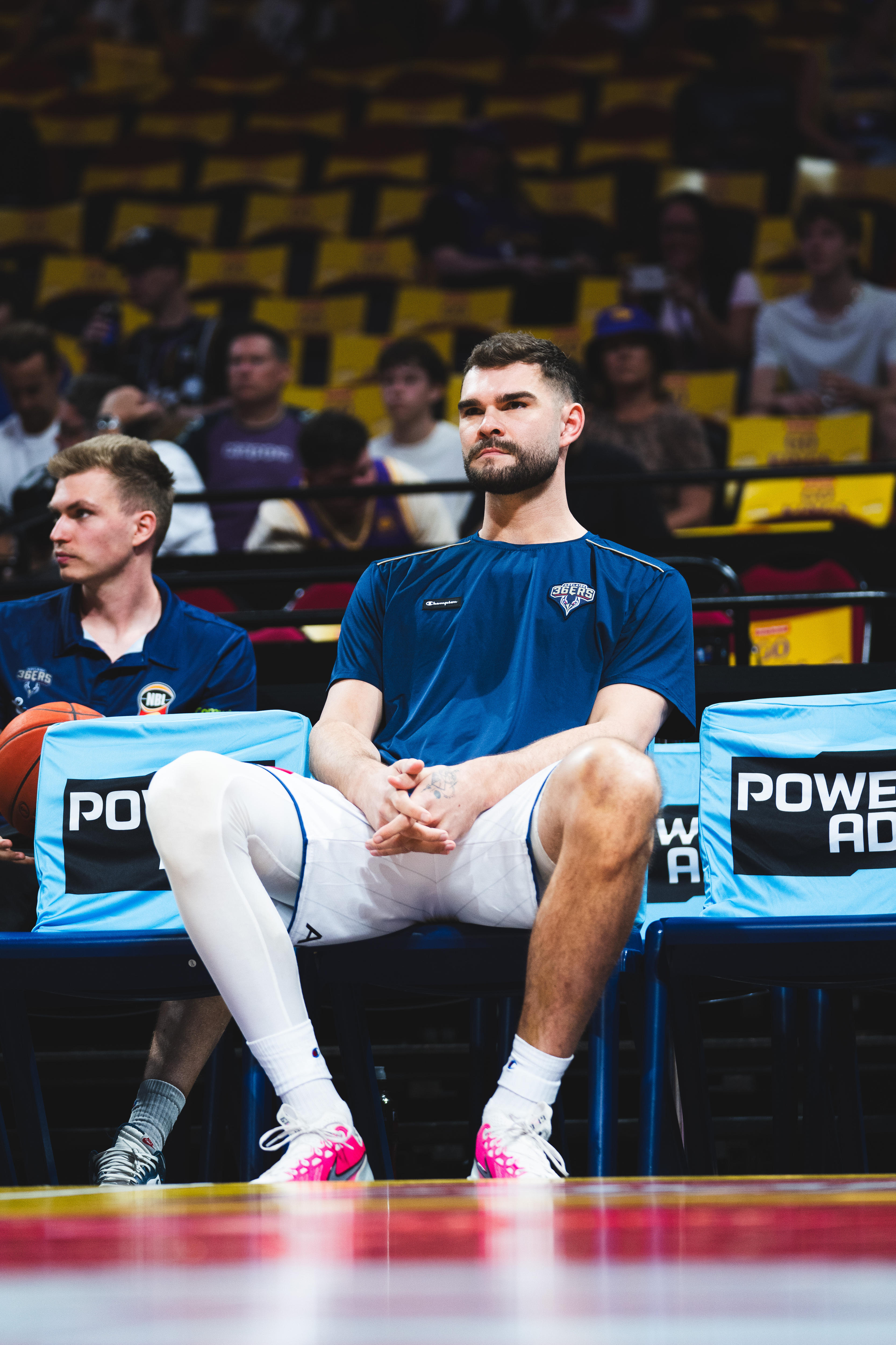 A man sits courtside while wearing compression socks over his right leg