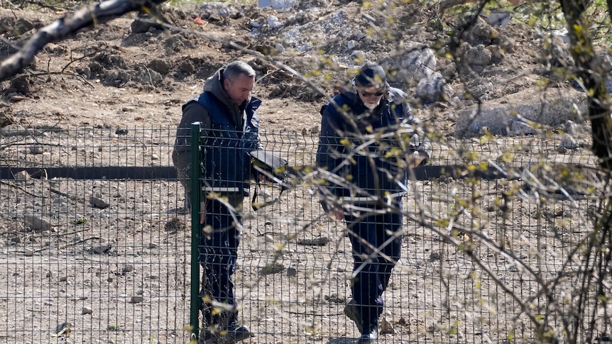 Two men inspect ground.