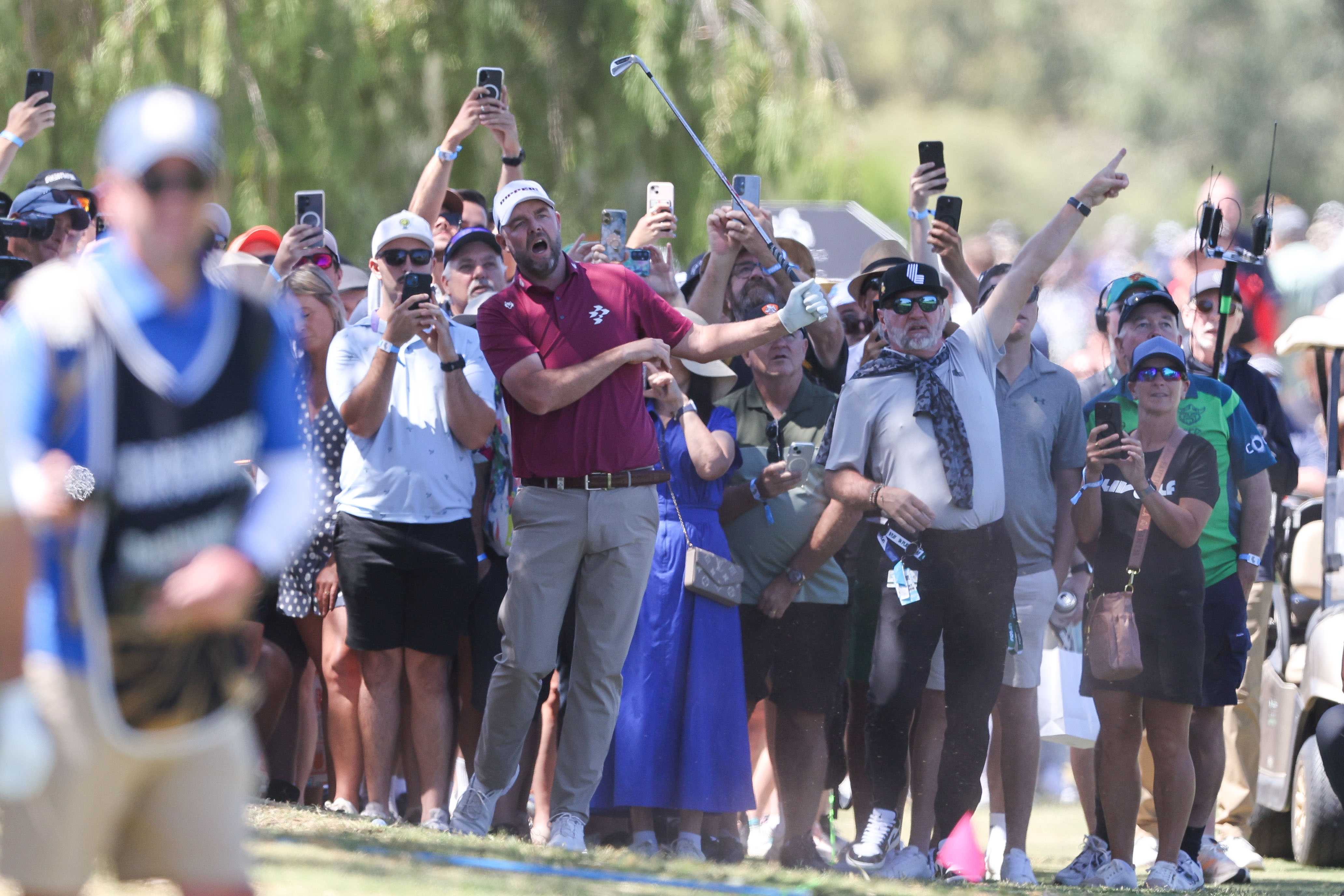 Golfers walking down a fairway at The Grange Golf Club during the LIV Golf Adelaide tournament, with spectators visible in the background.
