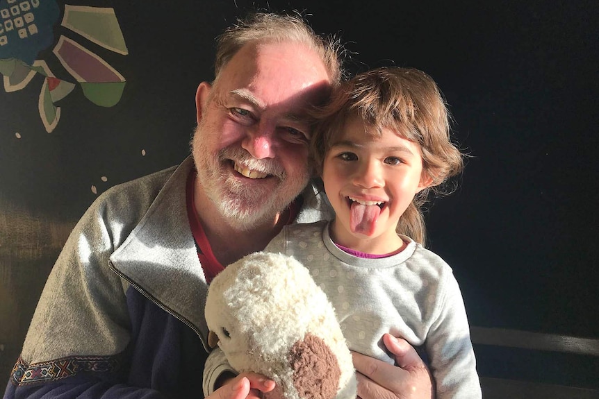 A young girl smiling as her father holds her in his arms