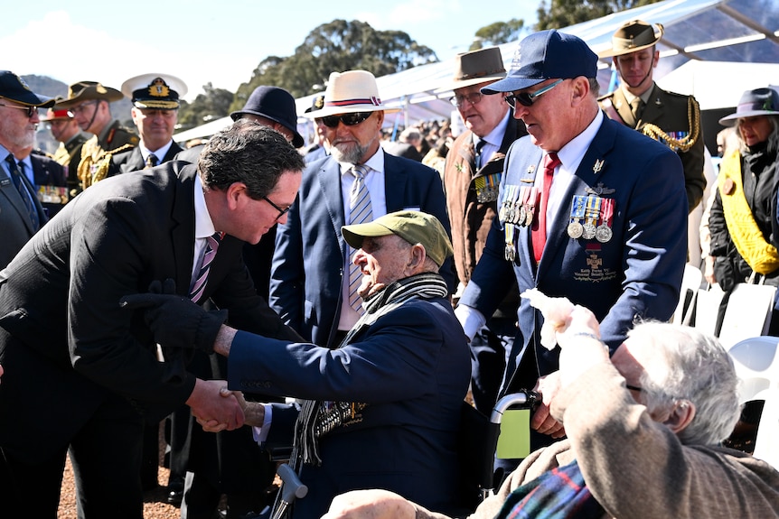 Matt leans down to shake hands with Keith in his wheelchair.