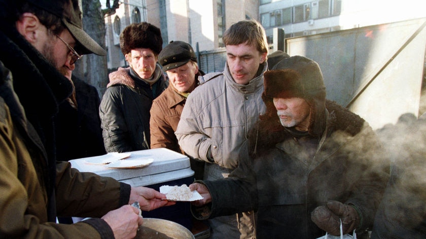 Then (1998): A homeless man receives free food in St Petersburg during Russia's economic crisis.