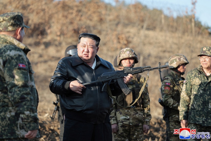 A man holding a gun amid soldiers. 
