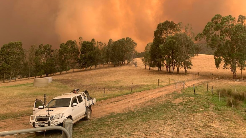 A smoke from a bushfire behind a white ute