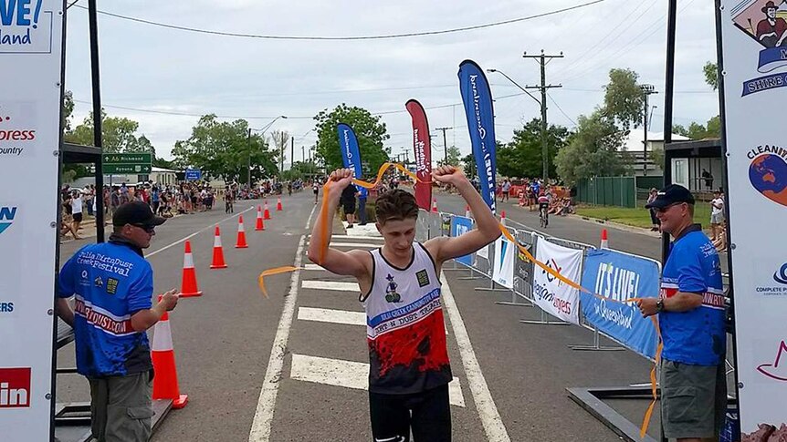 A man runs through the tape at the end of a triathlon