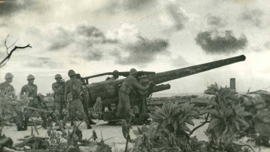 Wide sepia archive shot of a group of soldiers inspecting a large cannon.