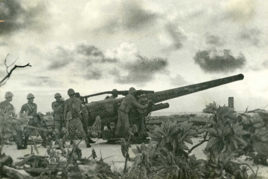 Wide sepia archive shot of a group of soldiers inspecting a large cannon.