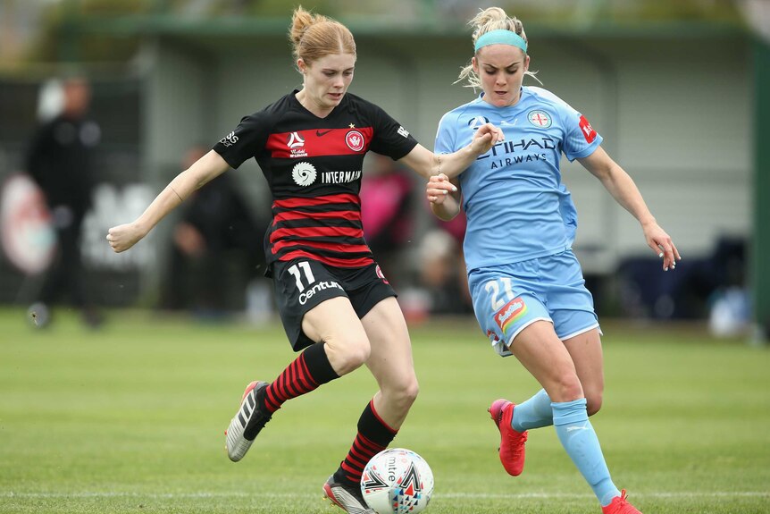 A Western Sydney Wanderers W-League player dribbles the ball next to a Melbourne City opponent.