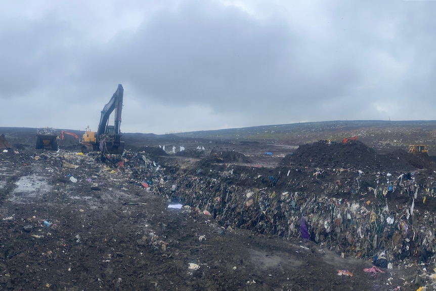A rubbish dump with an excavator 