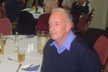 older man sitting at a table looking left