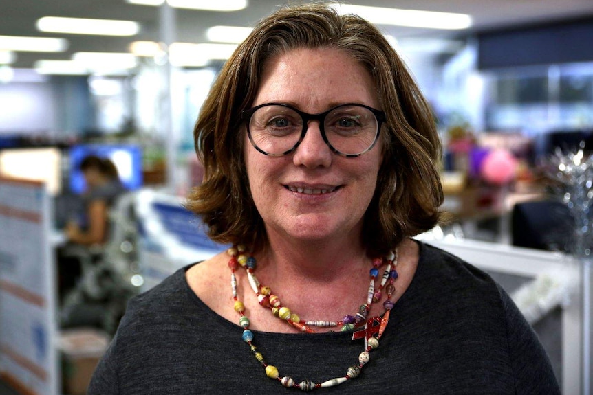 Lisa stands in an open plan office.