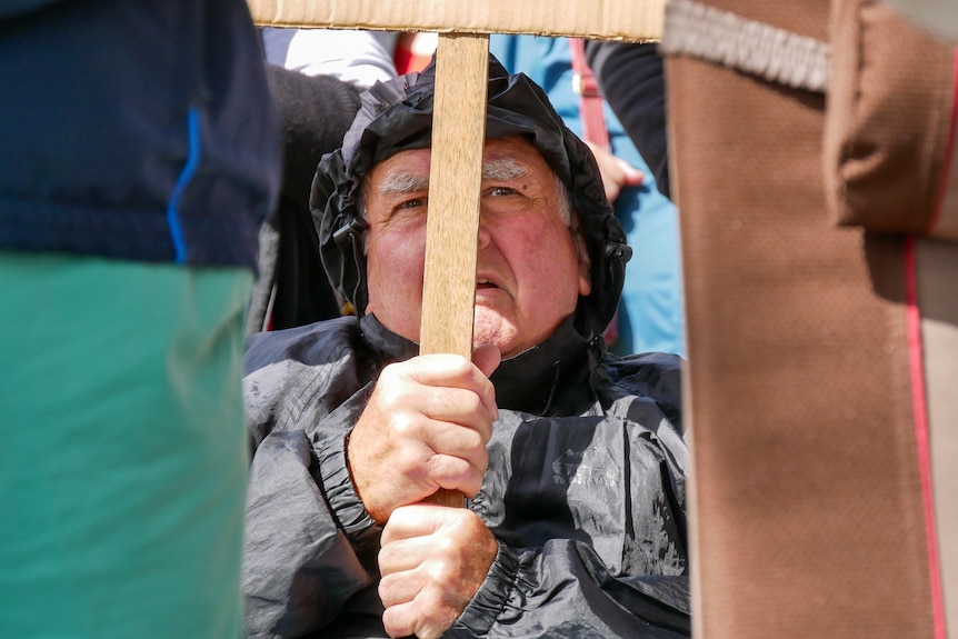 A man with his face behind the handle of a placard
