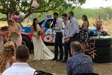 Bridal party stand in front of trophy truck